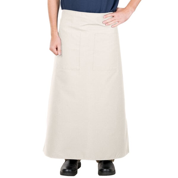 A person wearing an ivory Intedge bistro apron with 2 pockets.