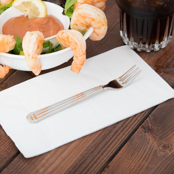 A Libbey stainless steel cocktail fork in a bowl of shrimp with sauce and a drink.