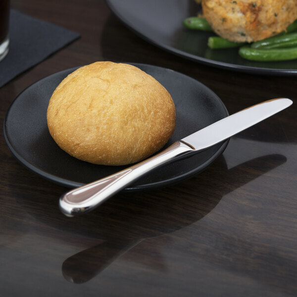 A black plate with a roll and a Libbey Aspen bread and butter knife.