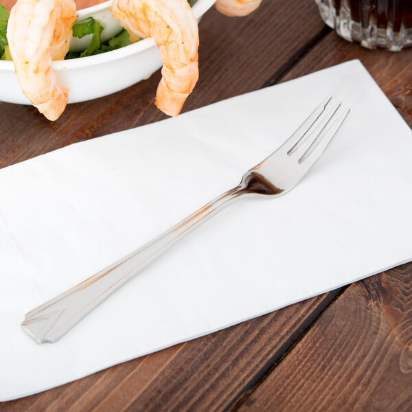 A World Tableware Varese cocktail fork on a napkin next to a bowl of shrimp.