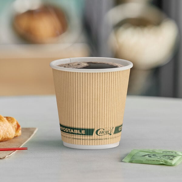 A close-up of an EcoChoice double wall paper hot cup filled with coffee on a table with a croissant.