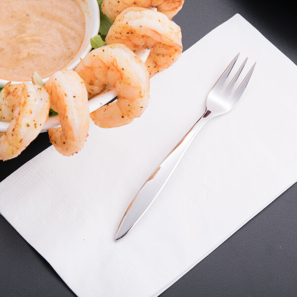 A Libbey stainless steel cocktail fork with shrimp and sauce on a napkin.