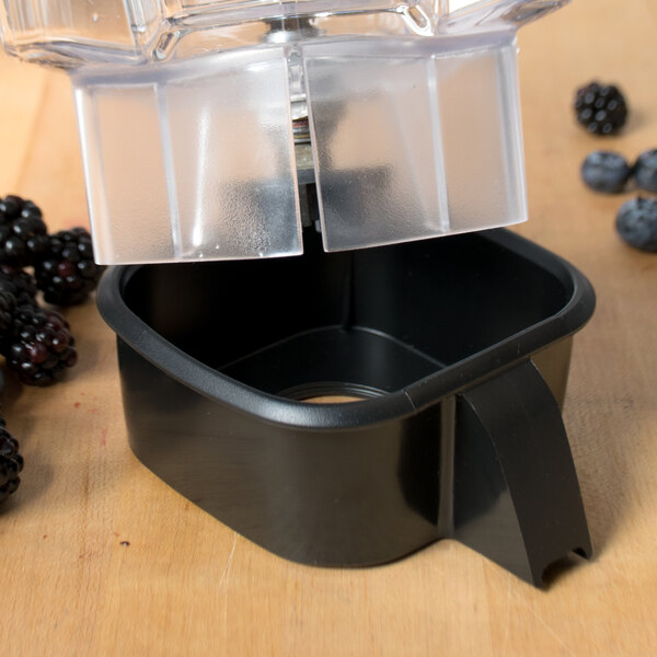 A black Waring jar pad on a table next to a blender with blackberries inside.