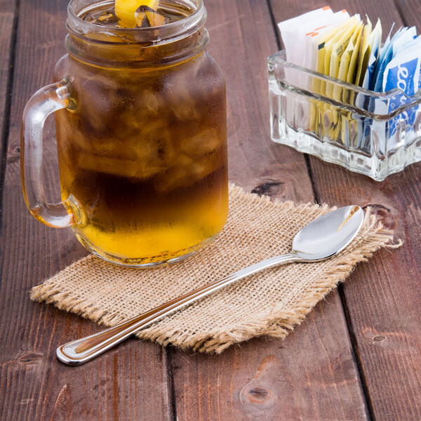 A glass mug with ice and a Libbey stainless steel iced tea spoon.