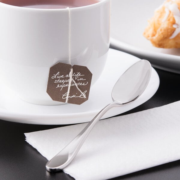A white demitasse cup of tea with a Reserve by Libbey stainless steel demitasse spoon on a saucer.
