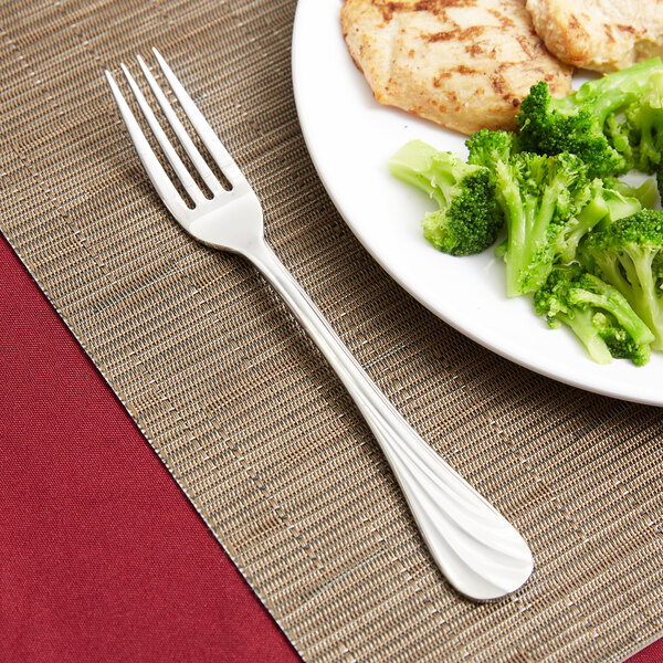 A Libbey stainless steel dinner fork on a plate of broccoli and chicken.