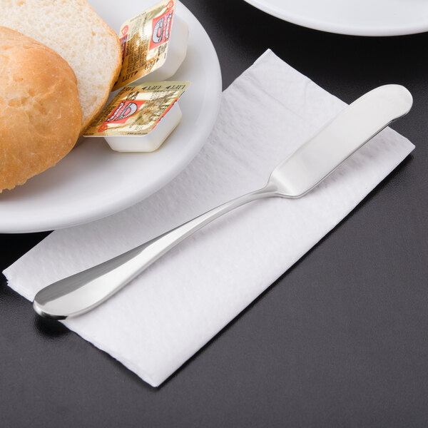 A plate with a Reserve by Libbey stainless steel butter spreader on a napkin with bread and butter.