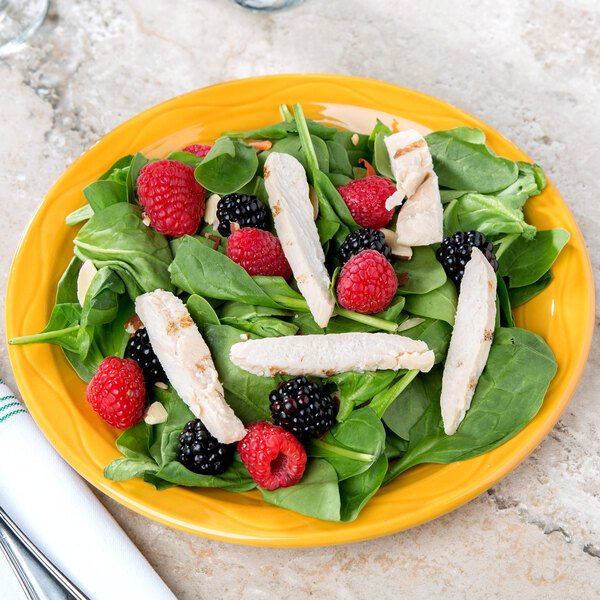 A close-up of a plate of salad with chicken and berries on a yellow Libbey Cantina porcelain plate.
