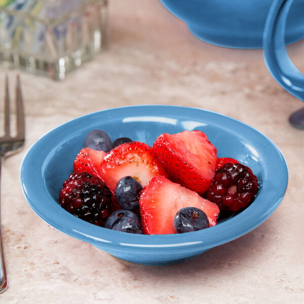 A Libbey blue porcelain fruit bowl filled with blueberries on a table.