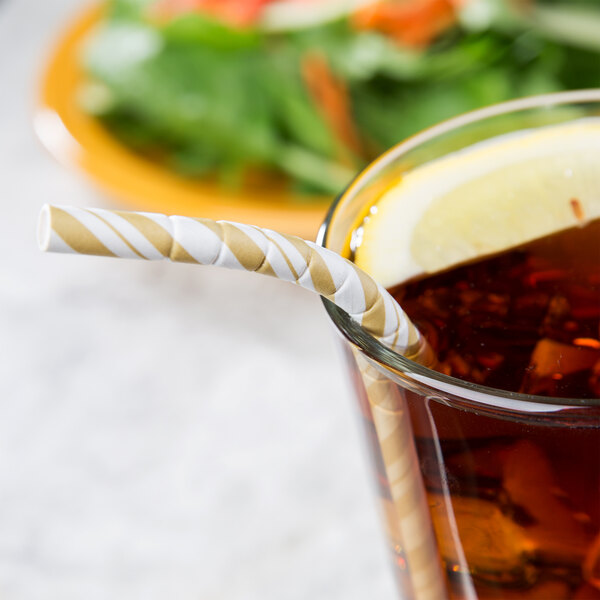 A glass of iced tea with a Creative Converting jumbo gold and white striped paper straw in it.