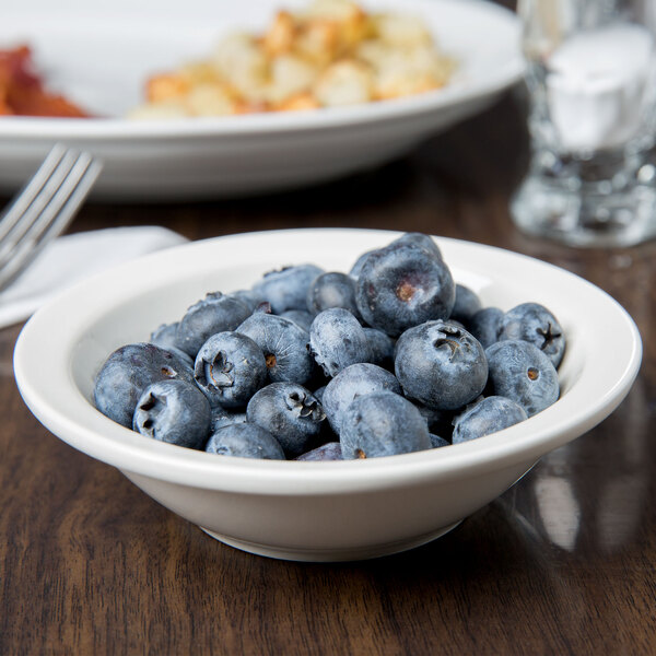 A Libbey Morwel porcelain fruit bowl filled with blueberries on a table.