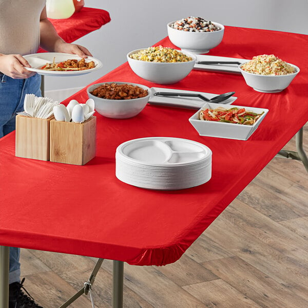 A red rectangular table with white bowls and plates of food.