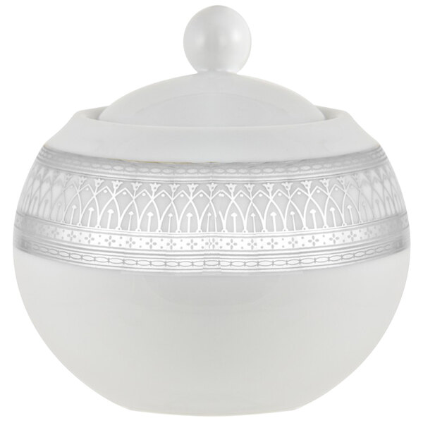 A white porcelain bowl with a silver lid and decorative design.