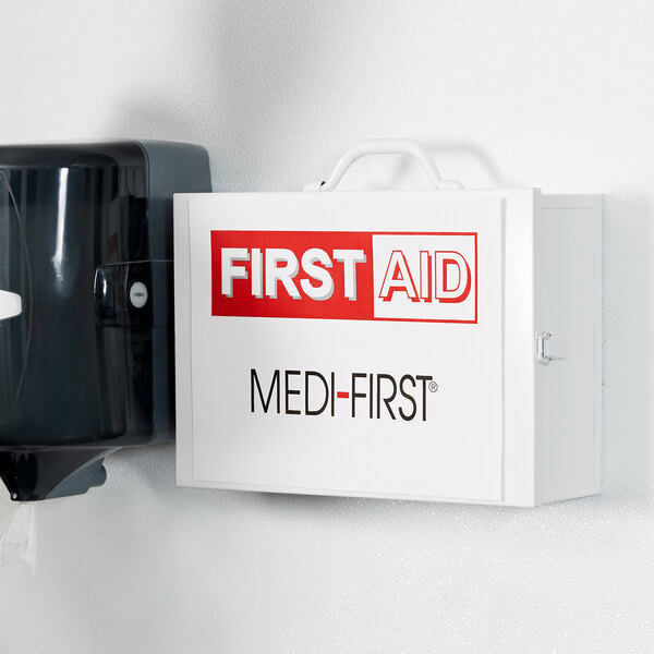 A white Medique first aid kit cabinet with red text on a black box.