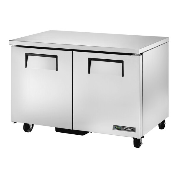 A silver True undercounter freezer with black handles.