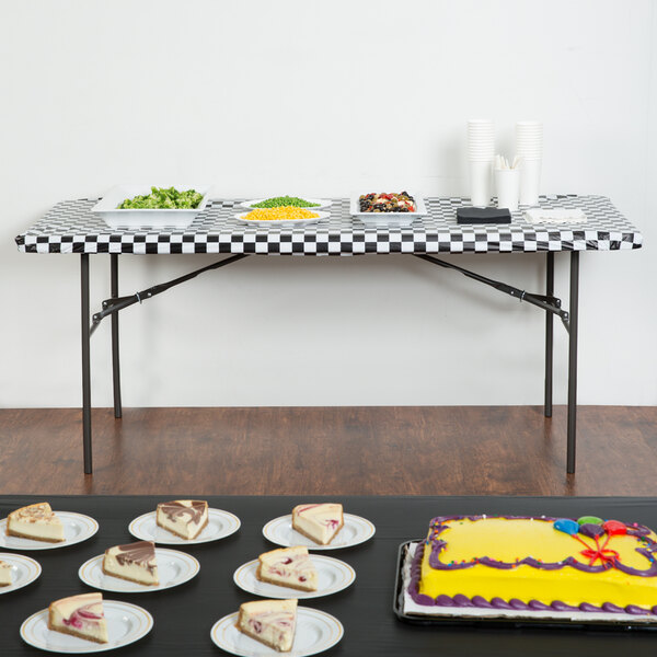A black check rectangular plastic tablecloth with elastic on a table with food on it.