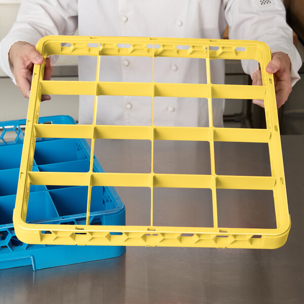 A chef holding a yellow Carlisle glass rack extender on a yellow plastic tray.