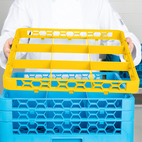 A person holding a yellow Carlisle plastic glass rack extender over a blue and yellow plastic basket.