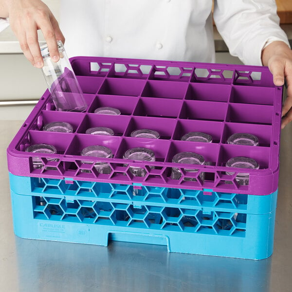 A woman using a purple and blue Carlisle glass rack with extenders on a counter.