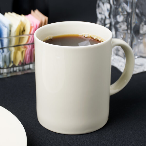 A white 10 Strawberry Street porcelain mug filled with brown liquid on a table.