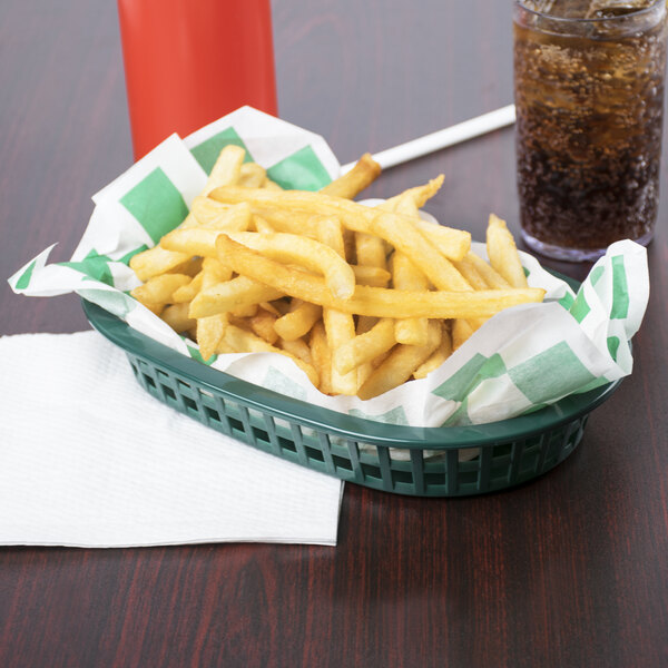 A Tablecraft oval forest green plastic fast food basket filled with french fries and a drink on a table.