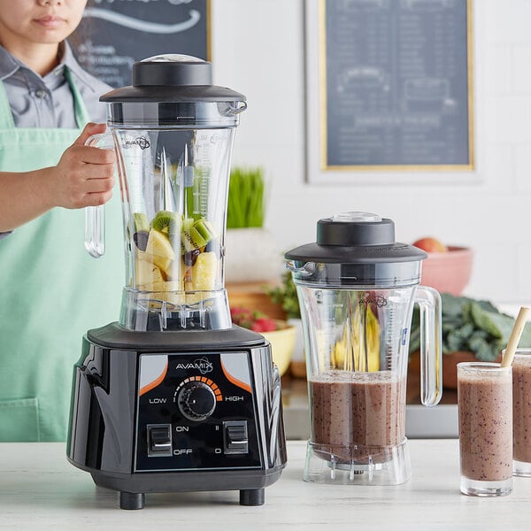 A woman in an apron uses an AvaMix commercial blender to make a brown smoothie.