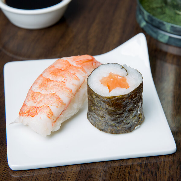 A Libbey ultra bright white porcelain square plate with sushi on a table.