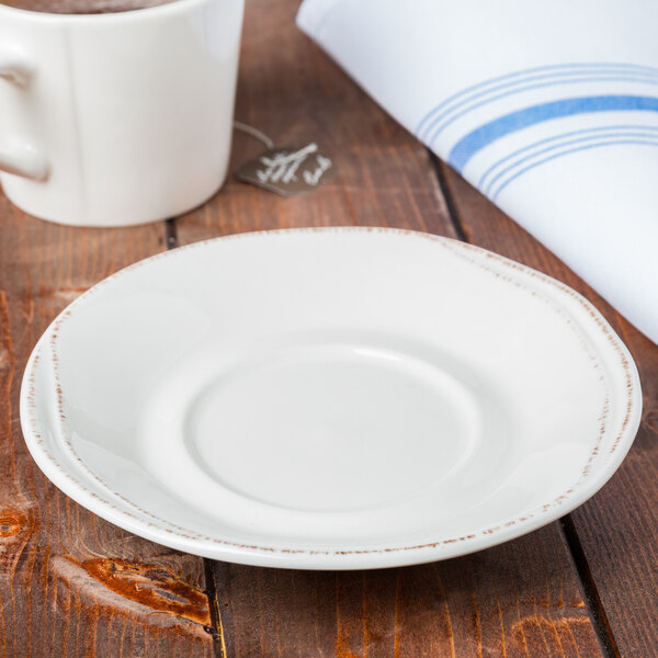 A Libbey Farmhouse ivory porcelain saucer on a white plate with a cup of coffee.
