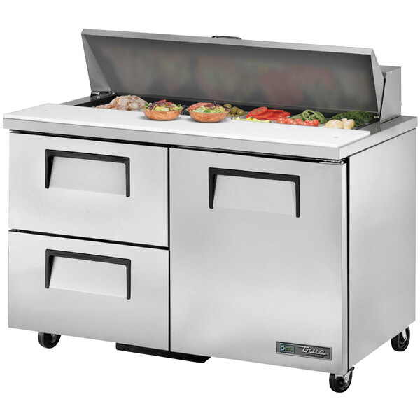 A True refrigerated sandwich prep table with doors and drawers on a counter with food on top.