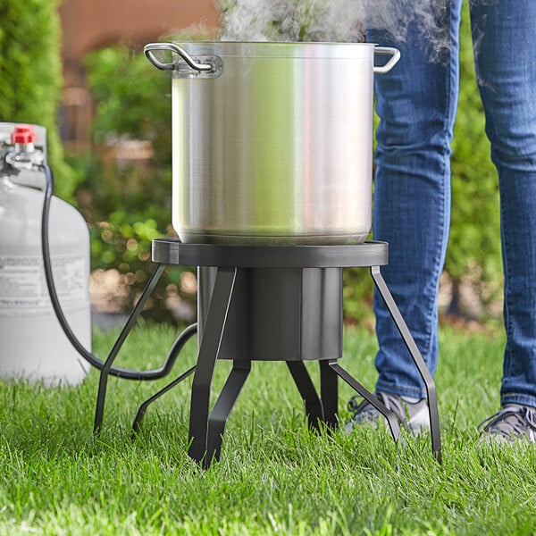 A person using a Backyard Pro outdoor patio stove to cook in a large pot.