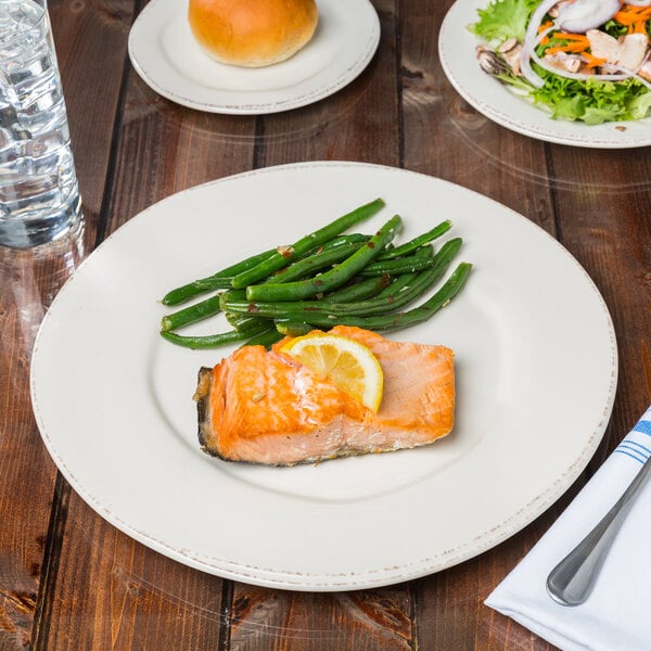 A Libbey Farmhouse porcelain plate with a piece of salmon and lemon wedges on it.