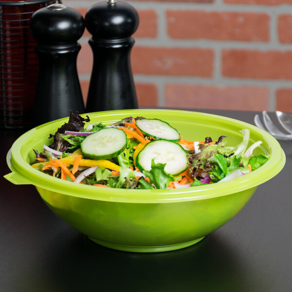 A green Fineline plastic bowl filled with salad on a table.