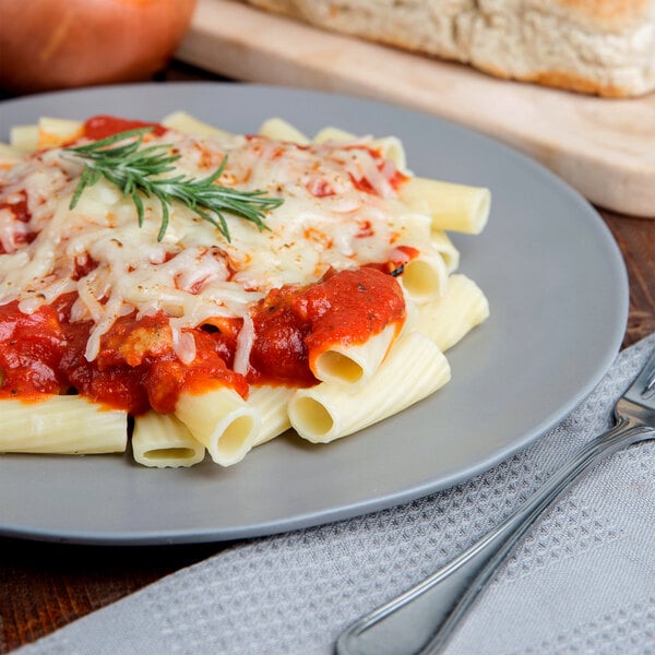 A plate of Regal rigatoni pasta with tomato sauce and cheese and a fork.