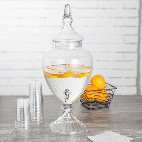 A Fifth Avenue Crystal glass beverage dispenser filled with liquid and lemons with a tap.