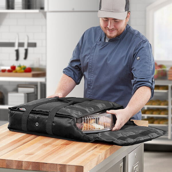 A man using a ServIt insulated deli tray and party platter bag to hold food.