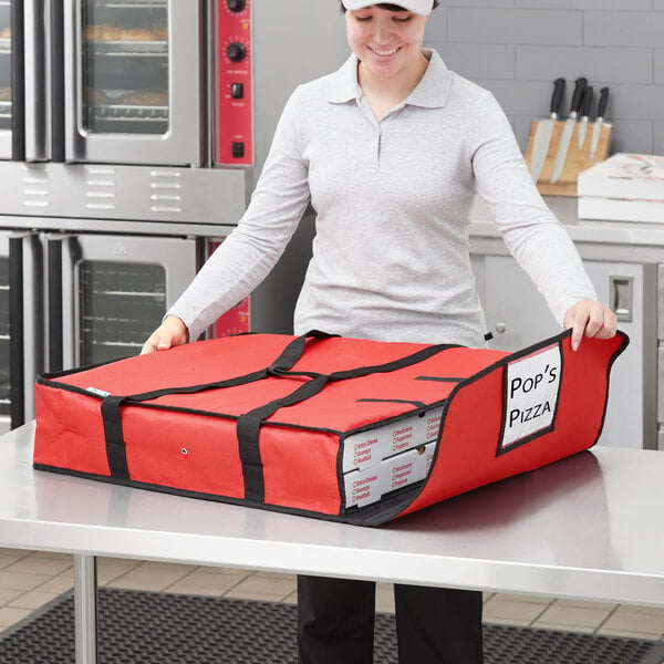 A woman holding a red Choice insulated pizza delivery bag with a pizza box inside.