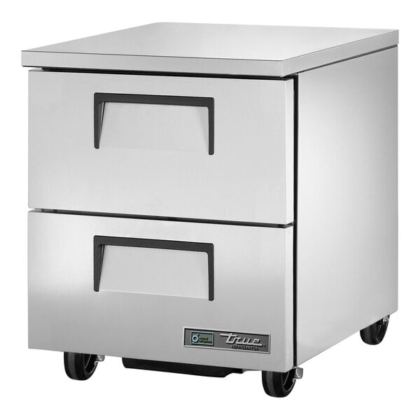 A white metal True undercounter refrigerator with two drawers on wheels.
