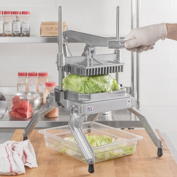 A person using a Nemco Easy LettuceKutter to cut lettuce in a plastic container.