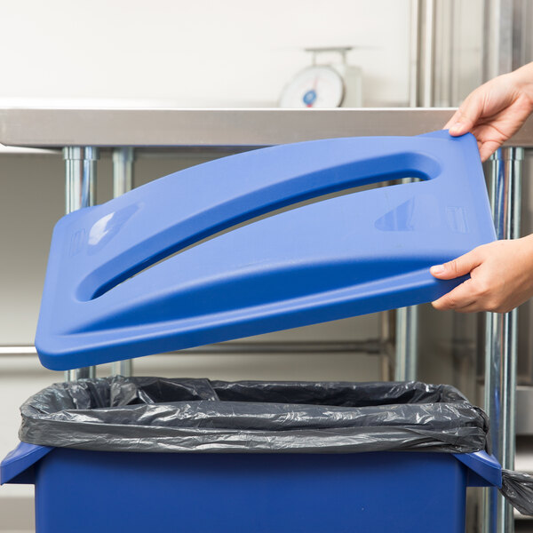 A hand putting a Rubbermaid blue plastic lid into a blue Rubbermaid trash can.