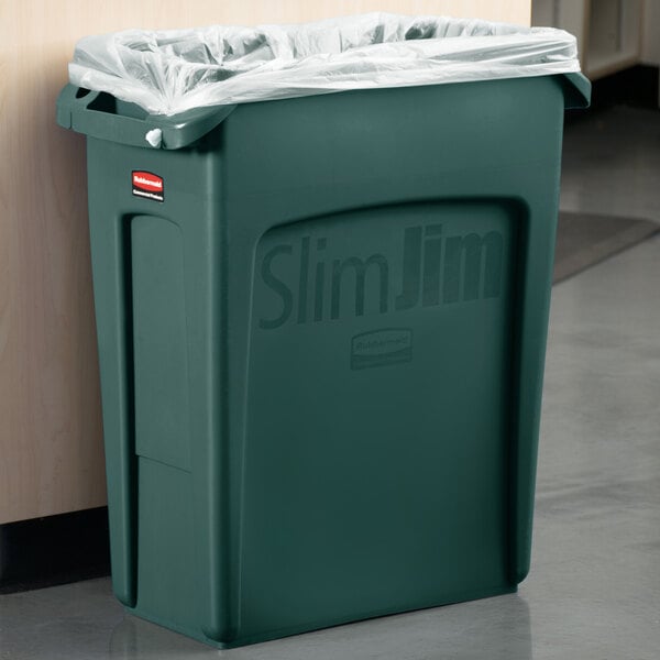 A green Rubbermaid Slim Jim trash can with a clear plastic bag over it.