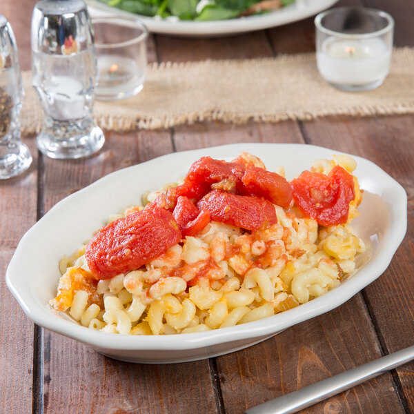 A Tuxton eggshell white china platter with pasta and tomatoes on it.