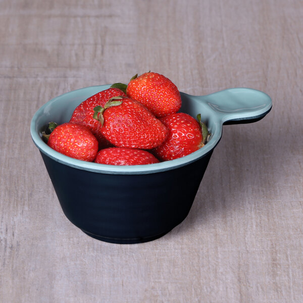 An Elite Global Solutions Durango melamine handled bowl filled with strawberries on a wooden table.