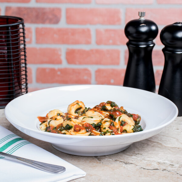 A bowl of pasta with vegetables and sauce in a white Elite Global Solutions melamine bowl.