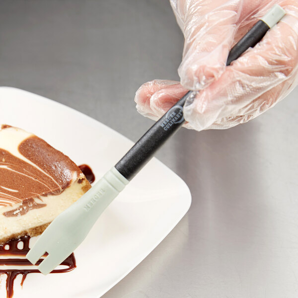 A person using a Mercer Culinary silicone plating tool to plate a piece of cake.