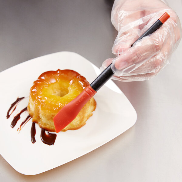 A person using a Mercer Culinary silicone brush to plate a pastry.