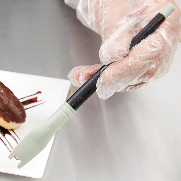 A person using a Mercer Culinary square notch silicone brush to plate chocolate cake.