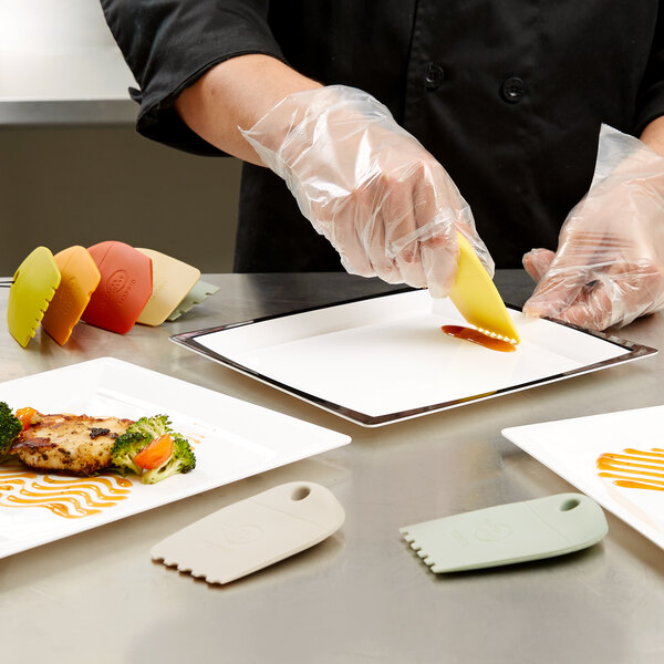 A person wearing Mercer Culinary gloves plating food with sauce.
