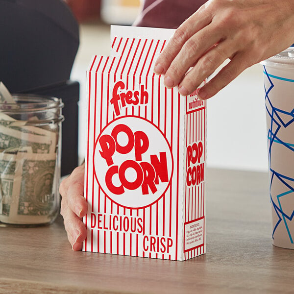 A person holding a Great Western popcorn box.
