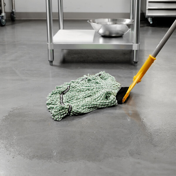 A Rubbermaid green medium microfiber looped end wet mop head on the floor.