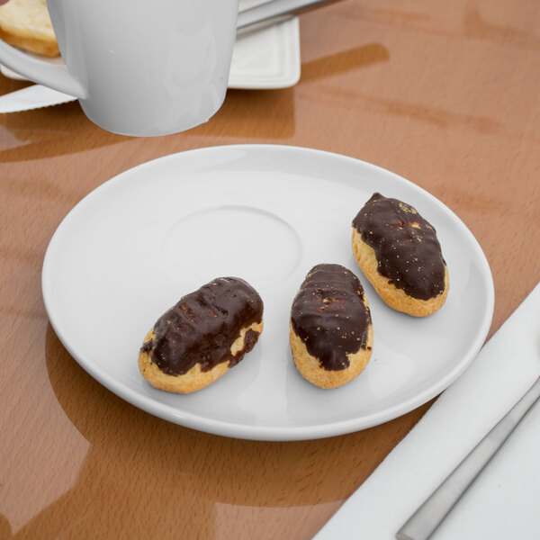 A Libbey white porcelain saucer with chocolate covered pastries on a table.